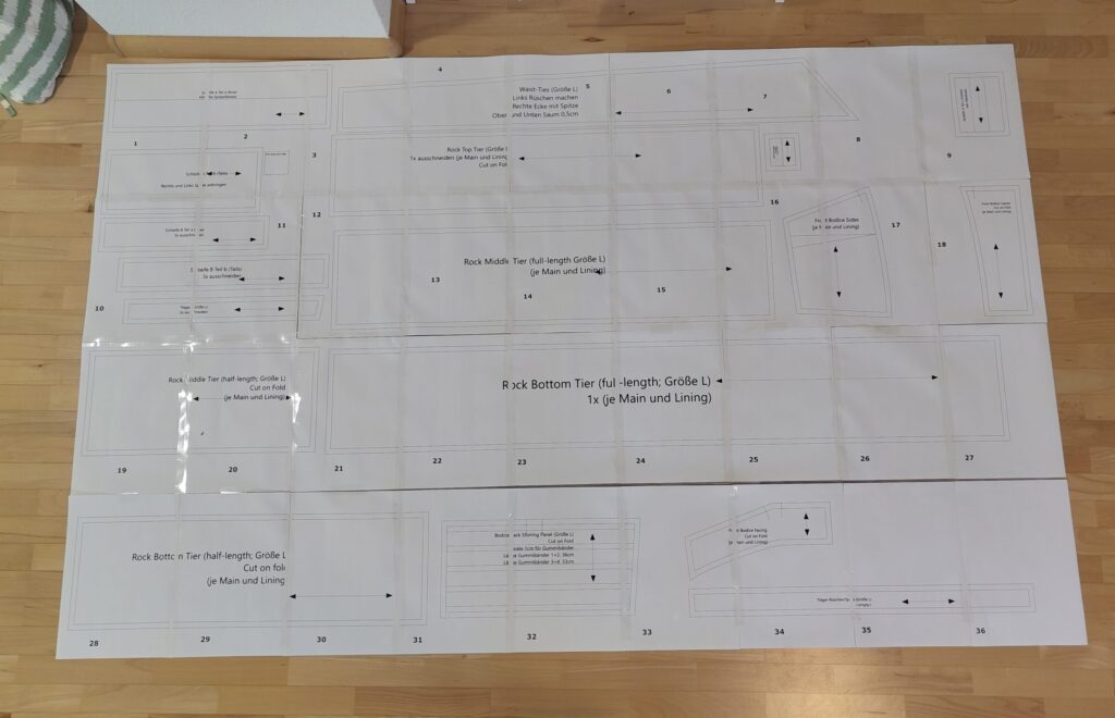 all the pattern-pieces on a big glued together piece paper consisting of 36 A4 sheets and laid out on the floor. The skirt pieces are mostly rectangles, the shirring panel is a trapezoid. there is also long wait-ties and all the pieces for the (wrong bodice)
